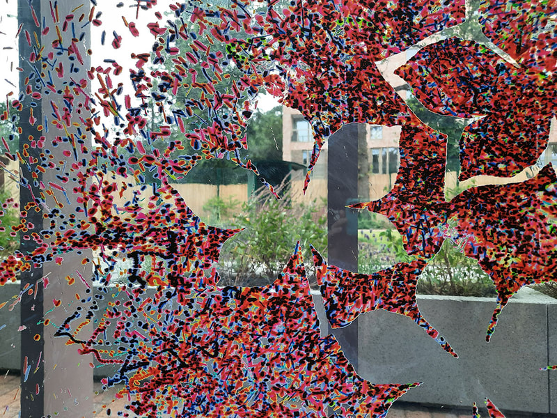 Coloured dots (red shades) creating silhoutted leaf shapes, with school garden seen in the gaps.