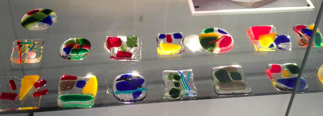 Image of small, multi-coloured pieces of fused glass arranged in two horizontal rows.