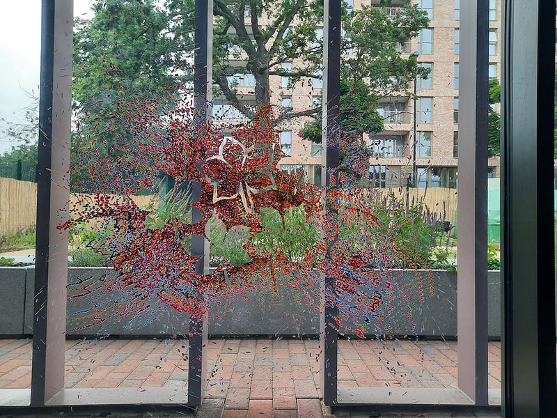 Coloured dots (red shades) creating silhouetted leaf shapes, with school garden seen in the gaps.