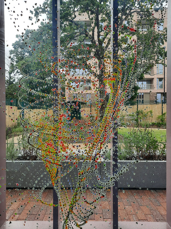 Multicoloured swirls of dots (red and yellow at centre), creating abstract shapes with a transparent background. The school gardens can be seen behind.
